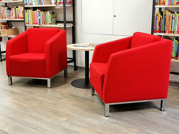 Sitzecke in der Elternbibliothek © Stadtbibliothek Kempen Zwei rote Sessel mit kleinem Tisch in der Elternbibliothek