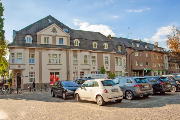 Parkplatz mit Wohn- und Geschäftshäusern im Hintergrund