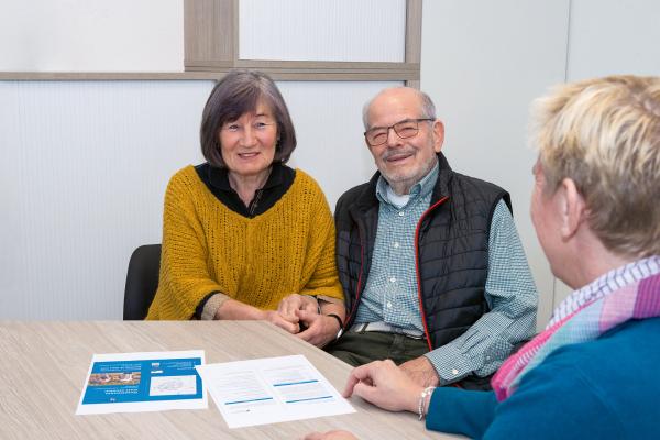 Senioren im Beratungsgespräch Eine Seniorin und ein Senior sitzen zusammen mit einer Mitarbeitenden an einem Tisch in einem Beratungsgespräch