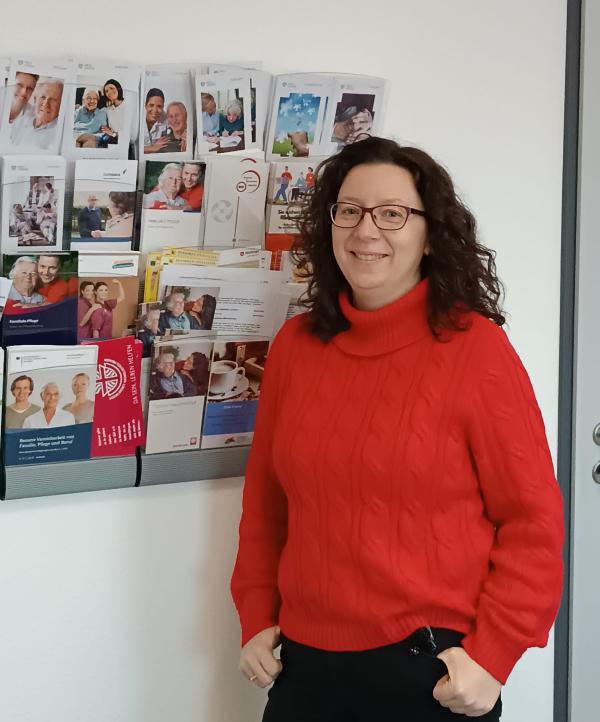 Marga Kammann Seniorenlotsin Seniorenlotsin Marga Kammann steht vor Wand mit einer Flyertafel