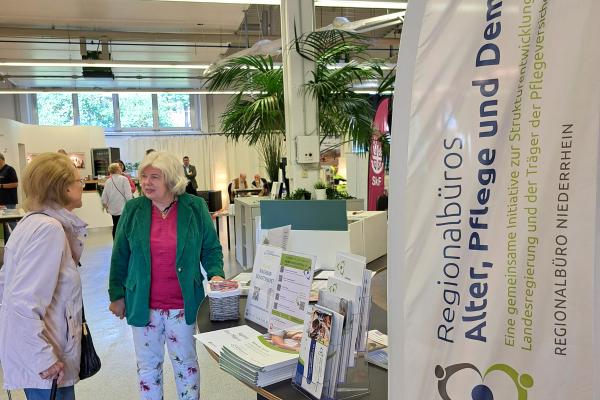 2 Frauen unterhalten sich an einem Infostand