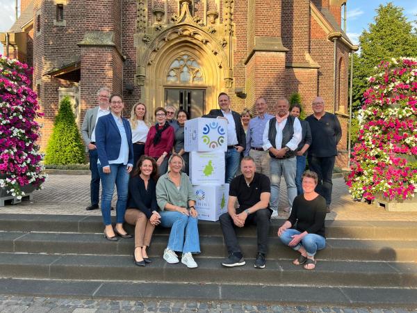 Bild: Lokale Aktionsgruppe der LEADER-Region Mittlerer Niederrhein e.V. Beteiligte Menschen stehen auf einer Treppe vor einer Kirche
