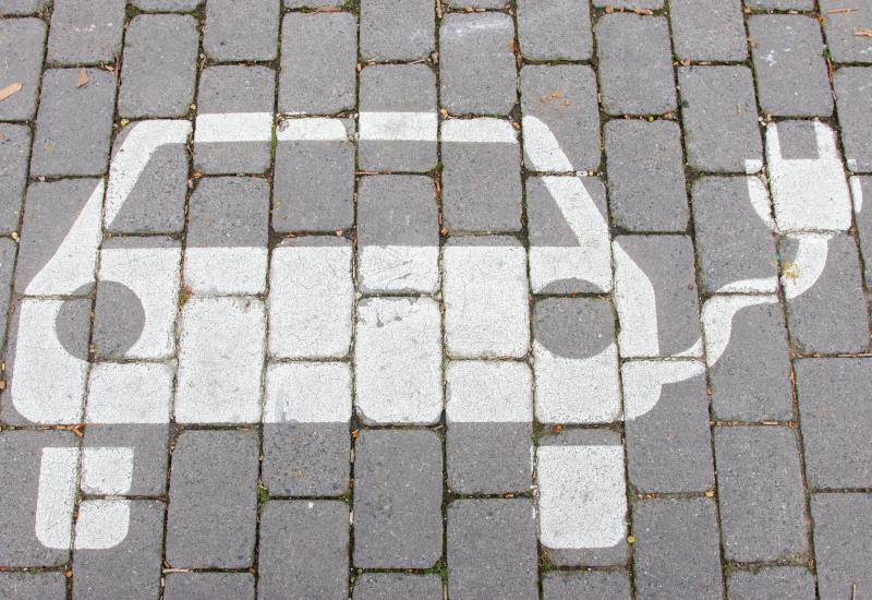 Grafik E-Ladestation auf grauem Altstadtpflaster auf einem Parkplatz
