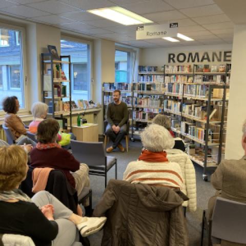 Lesung in der Bibliothek mit einem Leser und Besucherinnen